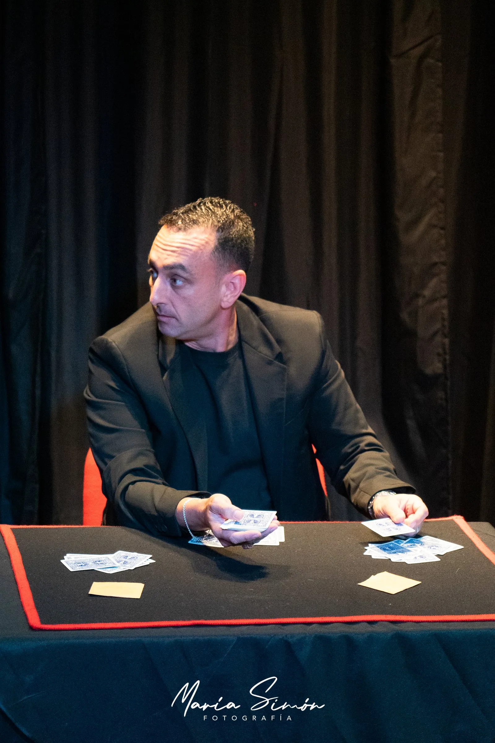 Larry sentado frente a una mesa de close-up con cartas