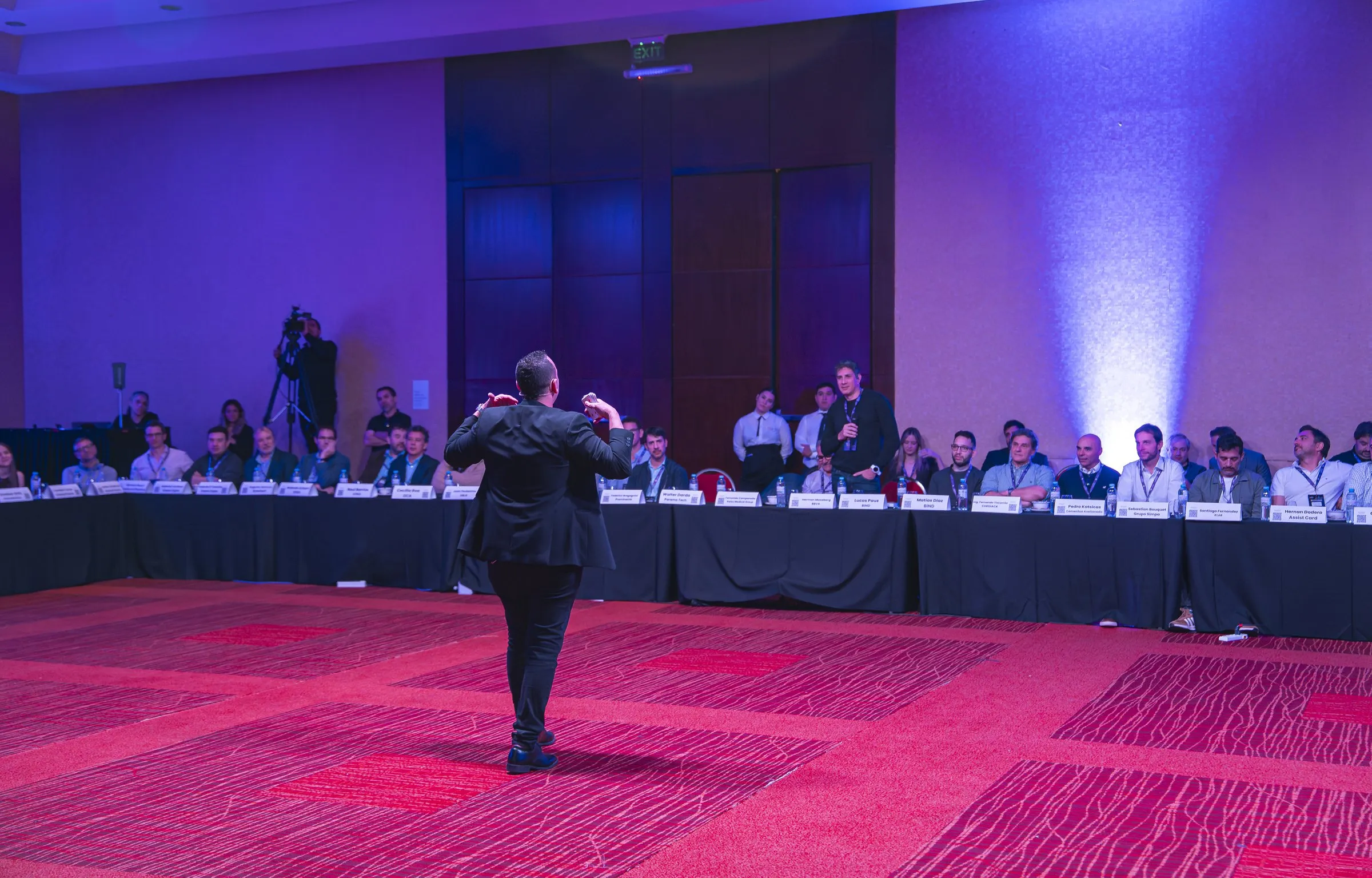 Larry de espaldas frente a un salón de congreso lleno