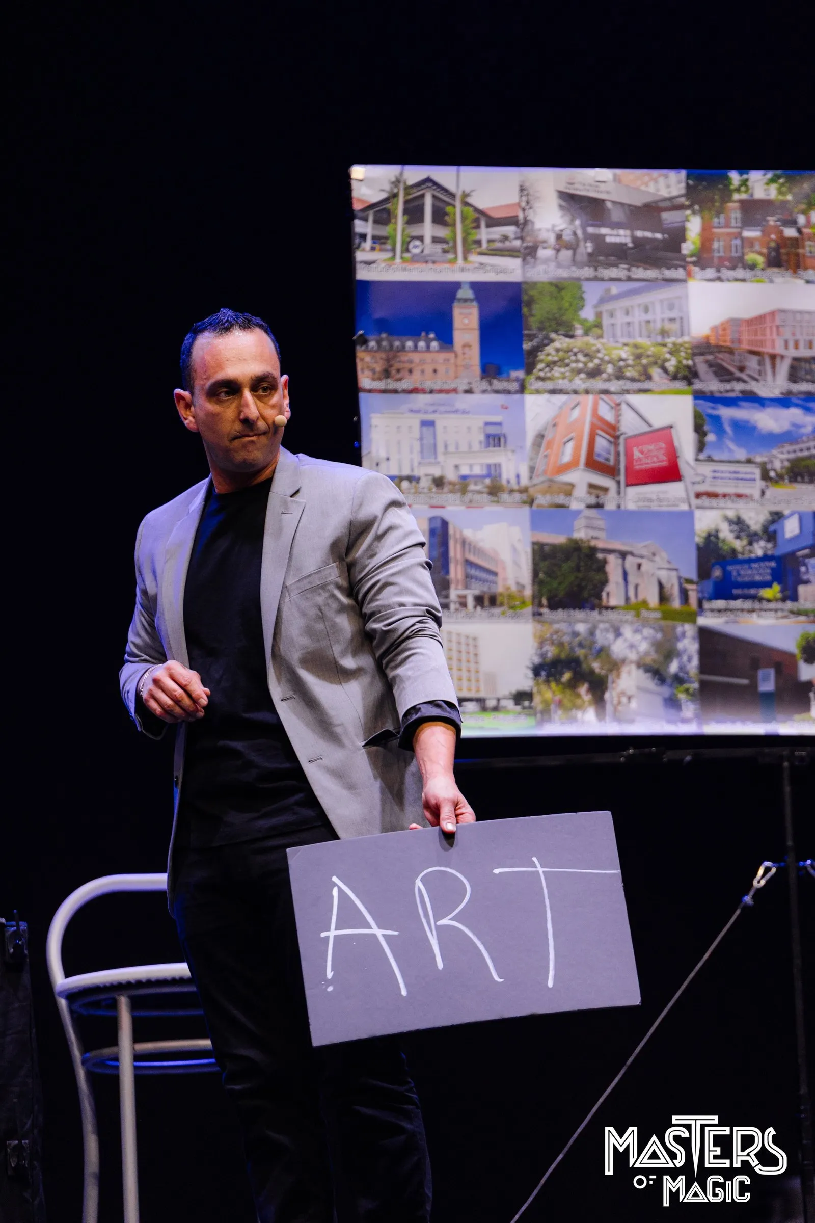 Larry sostiene un cartel con la palabra ART en el escenario de Masters of Magic